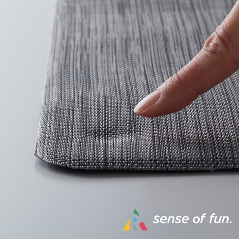 灰色編織紋理的廚房地墊，表面有紋理，一根手指輕壓在上面，顯示其柔軟度。
