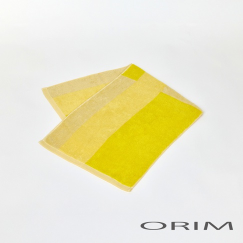 一條由淺黃至亮黃色塊拼接的純棉毛巾，帶有細膩的紋理，呈現簡約的幾何圖案。