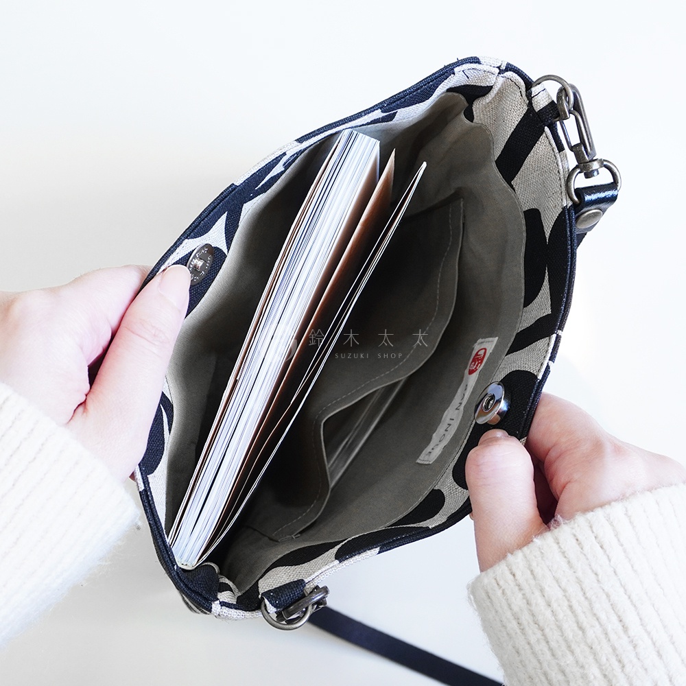 BAN INOUE 自然織紋麻布斜背包，內側印有「鈴木 SUZUKI SHOP」及日文「moni moni」字樣，包內可見筆記本。