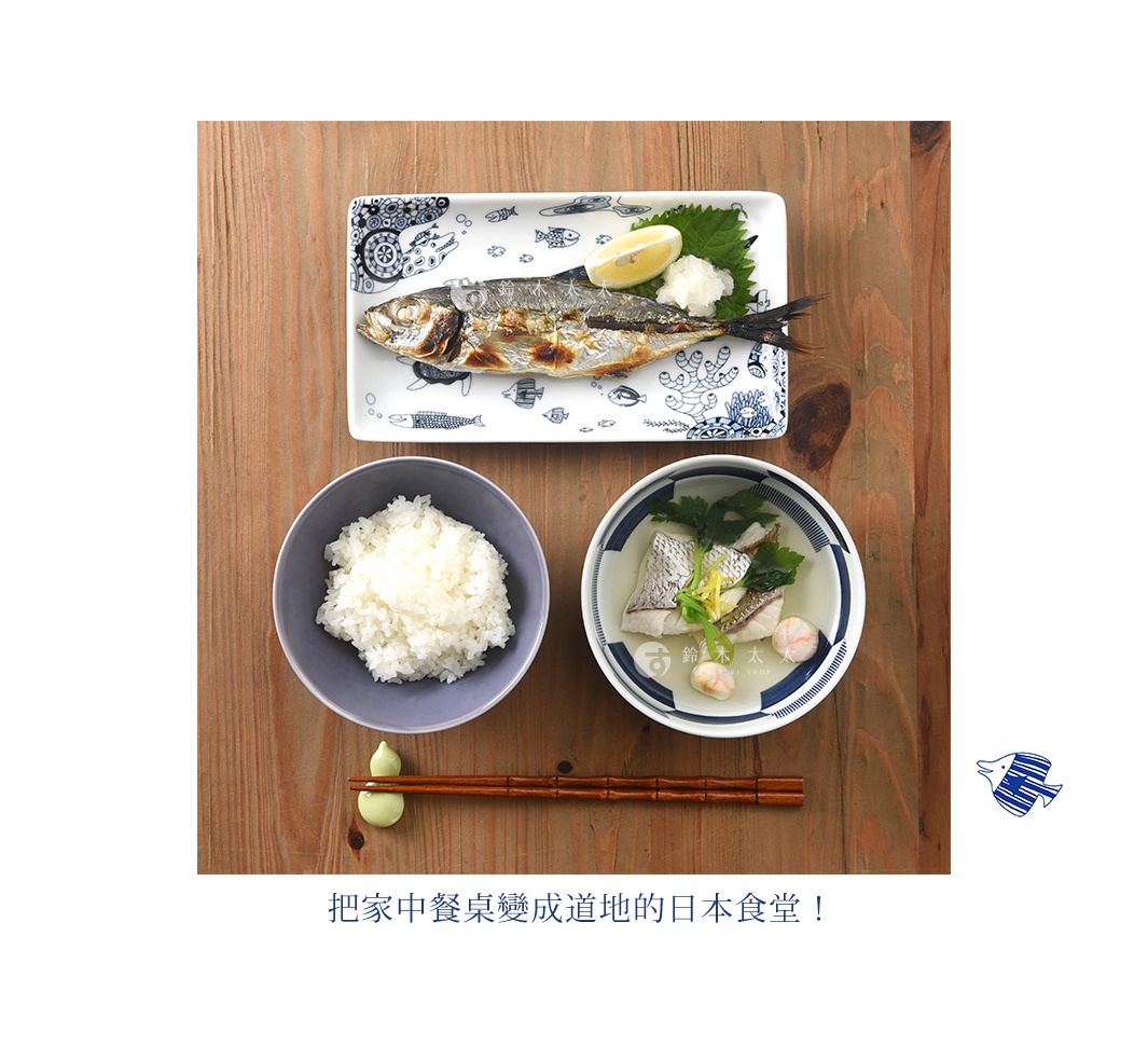 長方餐盤上盛有烤魚、檸檬片和蘿蔔泥，盤身飾有藍色魚紋。一旁有盛裝白飯的灰色碗和盛裝魚湯的藍白邊碗，下方擺放著一雙木筷和綠色醬料。