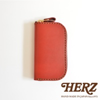 職人手作皮革橢圓形拉鍊鑰匙包，紅色，附有金色拉鍊和品牌標誌。