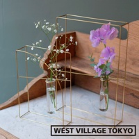 兩個黃銅書本造型掛擺兩用花器，分別裝有白色滿天星和紫色鈴蘭，以簡約的線條和金色光澤呈現，展示了現代設計感。