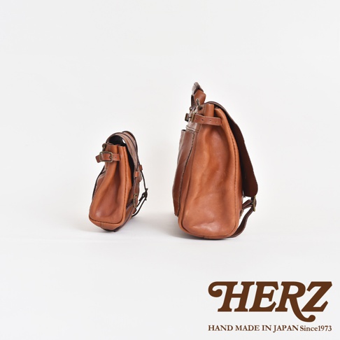 兩款棕色皮革復古郵差包，一較大一較小，皆配有可調節式帶扣和肩帶。