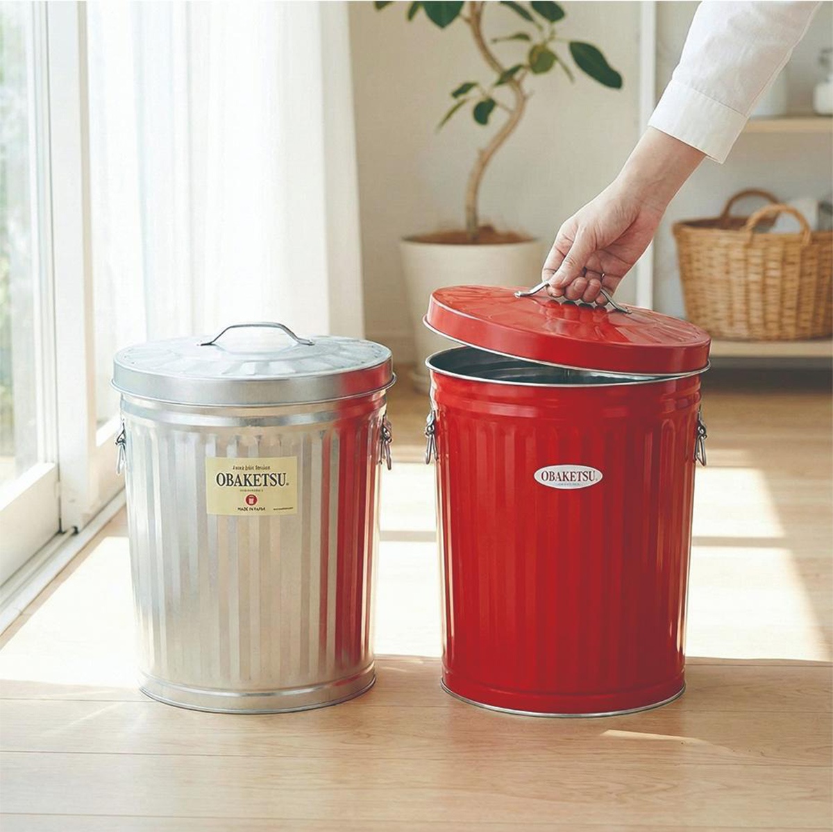 OBAKETSU 品牌紅色和銀色金屬垃圾桶，其中一個帶有蓋子，另一個則打開蓋子，上面標有 OBAKETSU 標誌。
