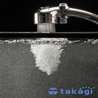 光澤銀色金屬蓮蓬頭，細密水柱噴灑入水中，水中產生大量白色微米氣泡，形成一團蓬鬆的氣泡雲。