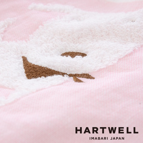 粉紅色紗布材質的嬰兒浴巾，繡有白色絨毛的動物臉部圖案，深棕色繡線勾勒出眼睛和鼻子，質地柔軟。