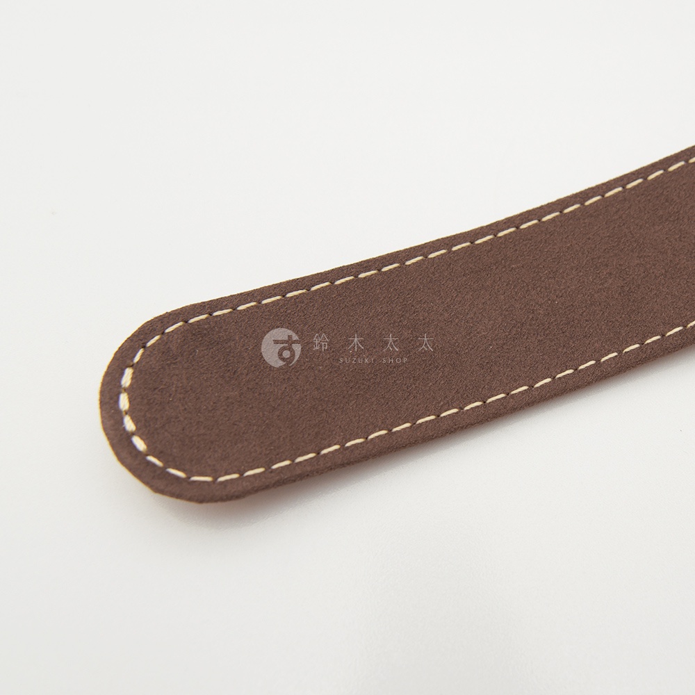 職人手作皮革肩墊，深棕色絨面皮革，米白色縫線，兩側有圓角設計，中央印有品牌標誌。