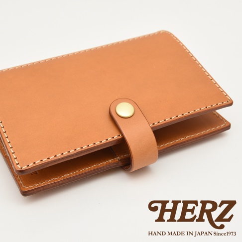 職人手作皮革記事本書套，採用天然棕色皮革，以白色車線縫製，設有金色金屬按扣，質感溫潤。