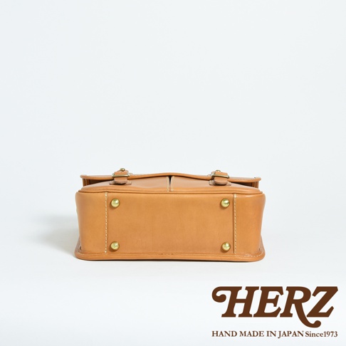 職人手作皮革商務休閒兩用單肩包 CW-10，採用溫暖的棕褐色皮革製成，搭配金屬扣環和鉚釘，設計簡潔大方，質感紮實。