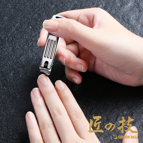一只手正使用銀色不鏽鋼曲刃指甲剪修剪另一隻手的手指甲。指甲剪具有金屬拉絲表面和直立的切割刃。
