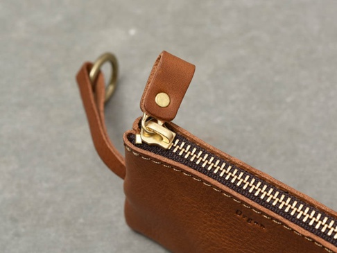 職人手作皮革Organ抽繩收納鑰匙包 (GS-65)，展示一褐色皮革小包的拉鍊細節，搭配金色拉頭與黃銅色D型環。