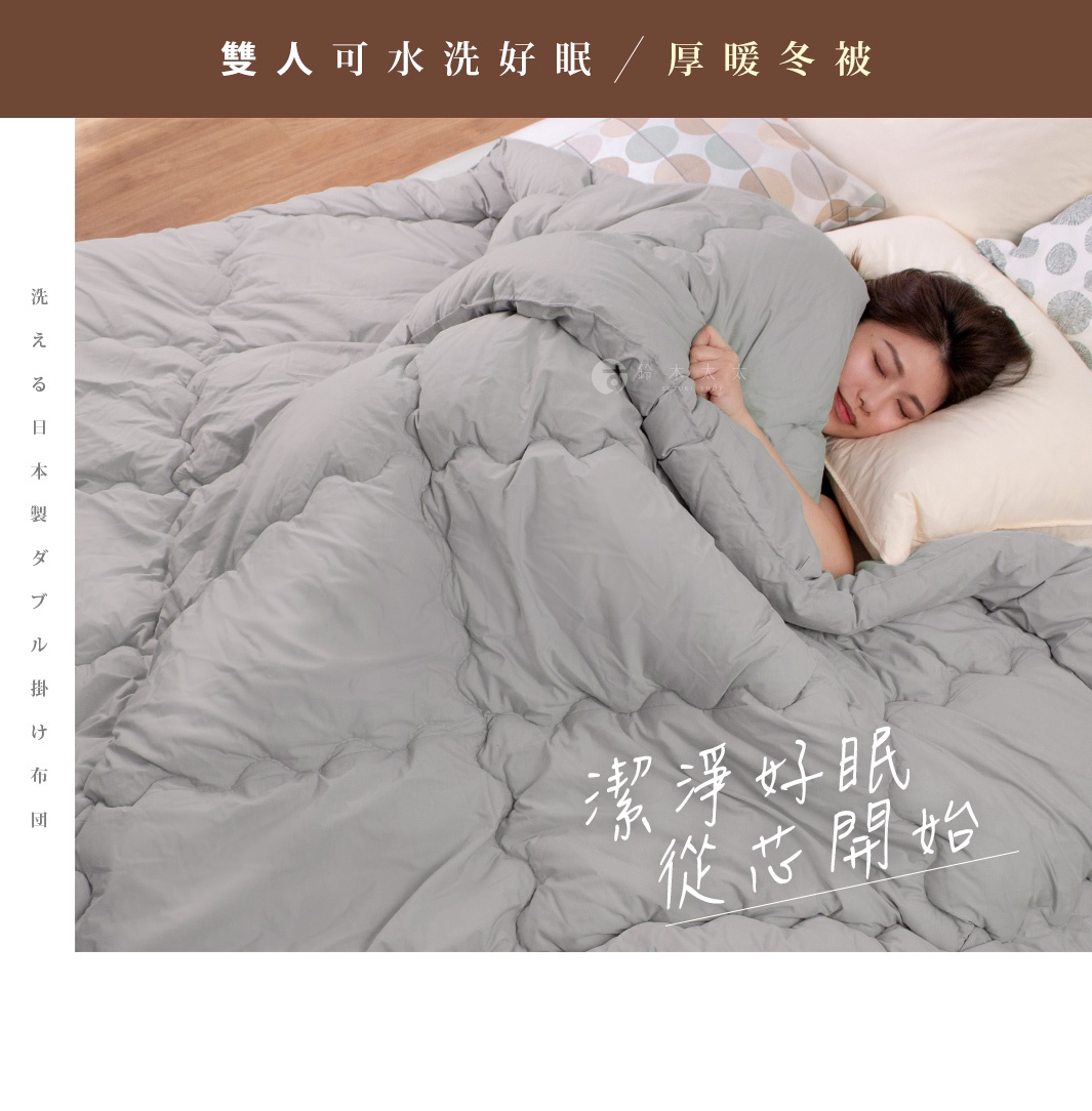 雙人厚暖冬被，採用灰色柔軟材質，覆蓋著一位女性，她正舒適地抱著枕頭熟睡。被子有明顯的絎縫紋路，營造出蓬鬆厚實的視覺效果。