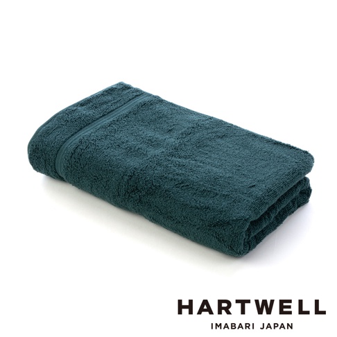 一條深綠色、柔軟、輕盈的今治毛巾，材質觸感細緻，折疊呈現，邊緣有精緻的縫線。