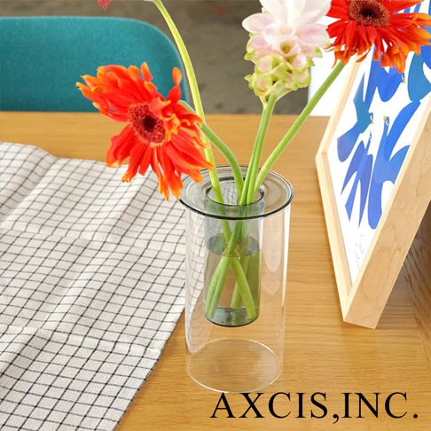 AXCIS 品牌 PINO 雙層可拆玻璃花瓶，擺放著橘色、粉色與紅色花朵，旁邊是具有藍色幾何圖案的畫框。
