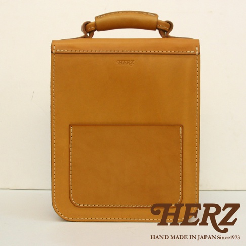 棕色皮革單肩兩用小方包，正面有一個方形外袋，頂部有提把，車縫線清晰，品牌標誌壓印於包包上方。