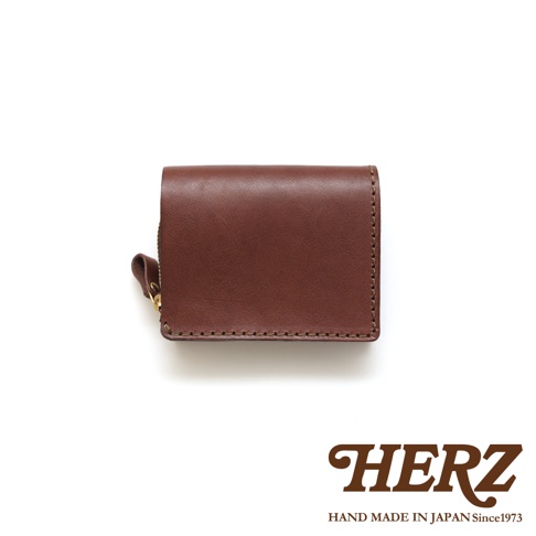 職人手作皮革小型雙折短夾，深棕色，正面光滑，側邊有縫線細節，左側附有金色拉鍊頭。