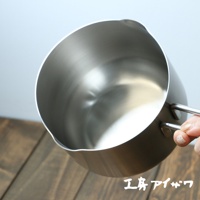 一個14公分的不鏽鋼雙口牛奶鍋，鍋身呈現銀色金屬光澤，設有兩個對稱的把手，鍋緣有方便傾倒的雙導流口設計。