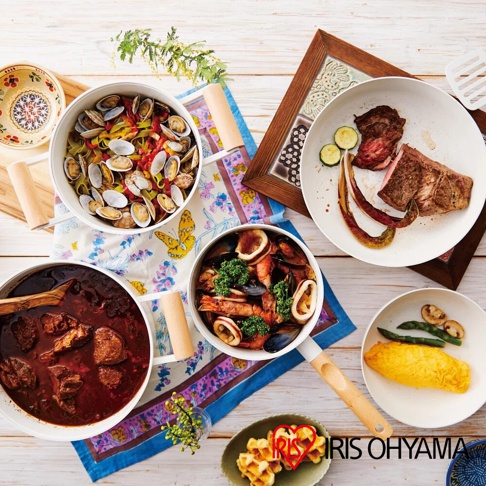 露歐頓 IH 不沾鍋具 10 件組 LUO-SE10，展示了三鍋料理：蛤蜊義大利麵、海鮮鍋與燉肉鍋，以及盤中的香煎牛排、歐姆蛋和鬆餅。鍋具為白色，配有木紋把手，搭配色彩鮮豔的餐巾與裝飾。