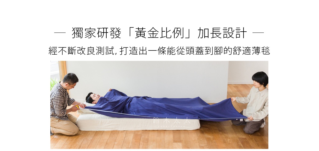 一名男子仰躺在床墊上，蓋著深藍色四層紗薄毯，兩旁各有一人協助展開薄毯，展示其超長設計。