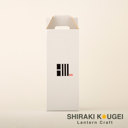 白色紙盒包裝，正面有黑色線條組成的圖案及紅色小印章。盒頂有提把。底部有「SHIRAKI KOUGEI Lantern Craft」字樣。