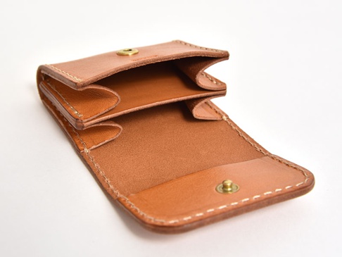 職人手作皮革雙折收納零錢包，採用淺棕色皮革製成，內部結構清晰可見，設有金屬按扣。