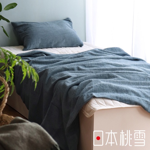 藍色雙面毛圈超長棉毛巾被蓋在床鋪上，一旁配有同色系枕頭。