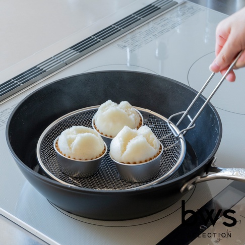 蒸煮三個白色饅頭在不鏽鋼蒸盤上，蒸盤架在有水的平底鍋中，手持金屬夾將蒸盤取出。