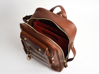 棕色皮革製直式收納袋中袋，附有多個拉鍊口袋、金屬扣和提把，內部空間可見紅色文件夾。