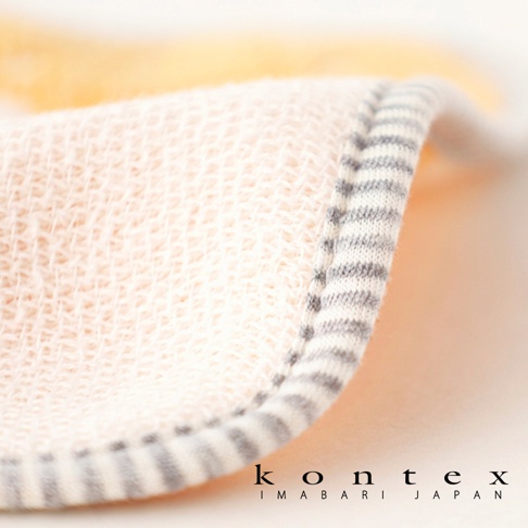 特寫鏡頭拍攝一張 KONTEX 今治純棉寶寶方巾，布料呈現自然米色且具有細緻的織紋質感，邊緣處縫製灰白條紋的棉質滾邊，整體風格簡約溫馨，右下角標註品牌名稱與產地。