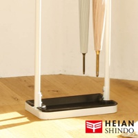 白色直立吊掛傘架，底部為黑色長方形集水盤，架身由白色金屬製成，吊掛著兩把分別為米白色與淺粉色的摺疊傘。