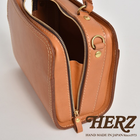 職人手作皮革兩用方形單肩包，採用柔軟的淺棕色皮革製作，搭配金色拉鍊及金屬配件，縫線清晰，設計簡約。