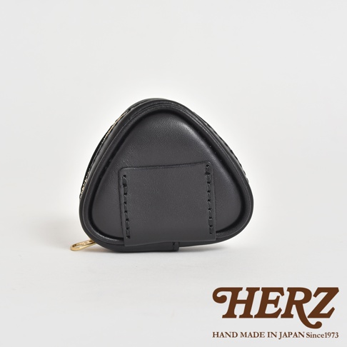 黑色皮革製成的三角飯糰造型小物收納包，具有簡潔的設計和精緻的縫線。包包一側有拉鍊開合，另一側裝飾有皮質掛帶。