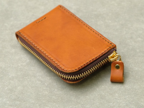 棕色皮革製作的拉鍊式卡片鑰匙包，帶有金色拉鍊和皮革拉環。
