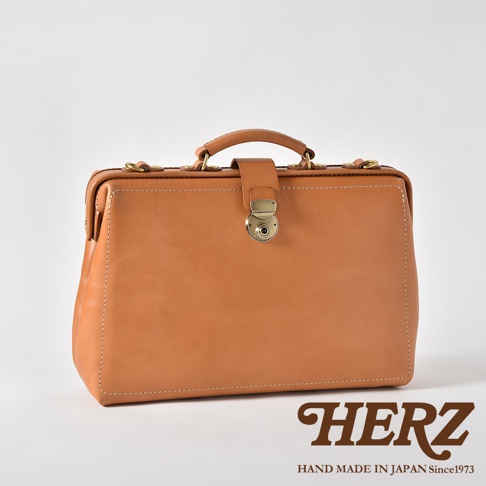 職人手作皮革軟式三用背包，以淺棕色皮革製成，配有金色金屬鎖扣和提把，風格復古。