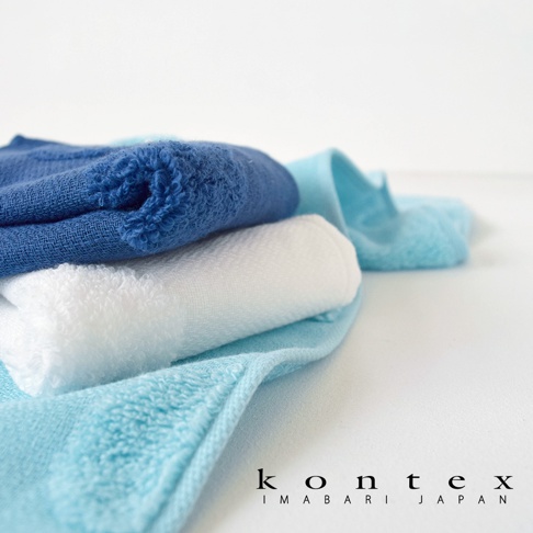 疊放的今治無撚紗質柔膚方巾，包含深藍、白色和淺藍色。方巾質地柔軟，表面有細緻的紋理。