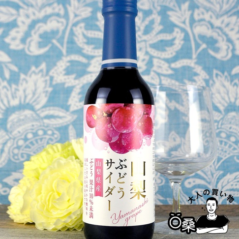 木村期間限定汽水，深色玻璃瓶裝，藍色瓶蓋，瓶身貼有描繪粉紅色葡萄串的標籤，旁為透明玻璃杯和黃色花束。