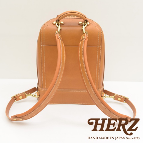 職人手作皮革立體商務後背包 R-3，採用淺棕色皮革，搭配金屬扣環和米白色車縫線，展現簡約大方的設計風格。