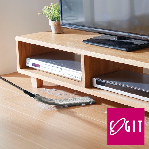 灰色伸縮式地板除塵縫隙清潔刷，刷頭為布質，正在清潔木質地板上的灰塵和毛髮，背景為木質電視櫃及內部擺放的影音設備。