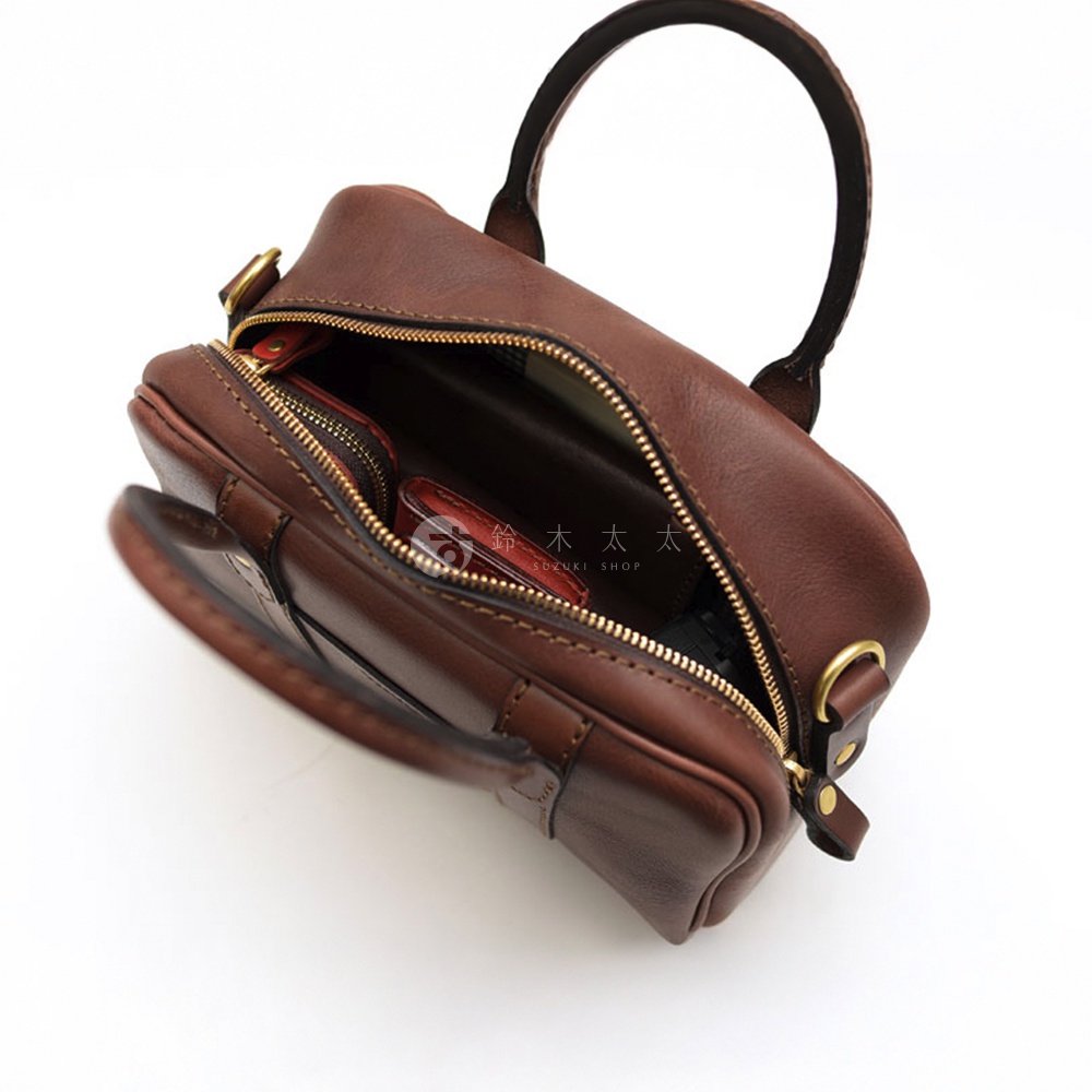 日本HERZ職人手作皮革兩用迷你波士頓包，深棕色圓潤包身，以金色拉鍊開口，露出內部零錢包和其他小物，經典簡約設計。