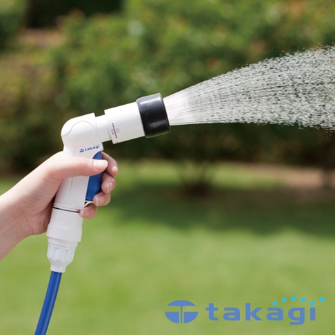 手持白色與藍色塑膠材質的澆花灑水槍，噴出細密水流，背景為綠色草地與模糊的樹木。