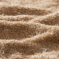 The LAST TOWEL 魔法瞬吸純棉柔毛巾，特寫展示其柔軟蓬鬆的純棉毛圈材質，呈現溫暖的淺褐色調，毛巾表面有自然的褶皺紋理。