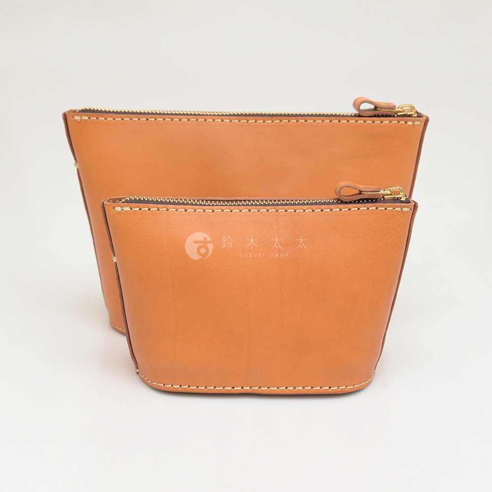 兩款淺棕色皮革三角收納包，材質為真皮，採用手工縫線，搭配金色拉鍊及皮革拉頭，其中一款較大，有品牌標誌。