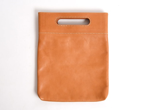 棕褐色皮革製成，方形直立式收納袋，頂部有長方形開口提把，袋身以白色縫線裝飾。