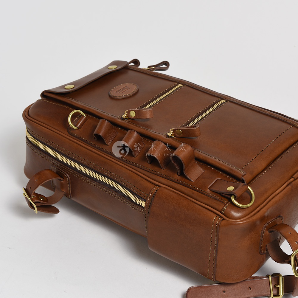 職人手作棕色皮革兩用多功能後背包，設有金色拉鍊、皮質提把、肩帶扣環和品牌標誌，風格經典。