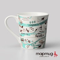 白色陶瓷馬克杯，印有手繪風格的大阪地圖，包含散步的貓咪、飛機、摩天輪、建築和地名，以藍綠色與棕色線條勾勒。