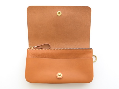 棕色皮革旅行收納長夾，開合處有金色按扣，設有拉鍊零錢袋和多個卡槽，側面有金色 D 型環。