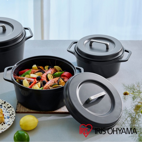 IRIS OHYAMA 萬用無水調理鍋，內含豐盛的燉煮料理，搭配上黑色鍋身與鍋蓋，以及旁邊的鮮黃檸檬與青檸。