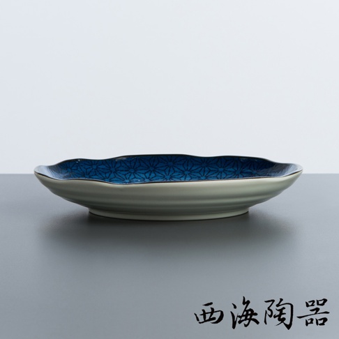 一個日本美濃燒淺圓盤，內側有藍色幾何圖案，邊緣為淺色，盤身有層疊的紋路，材質為陶瓷。