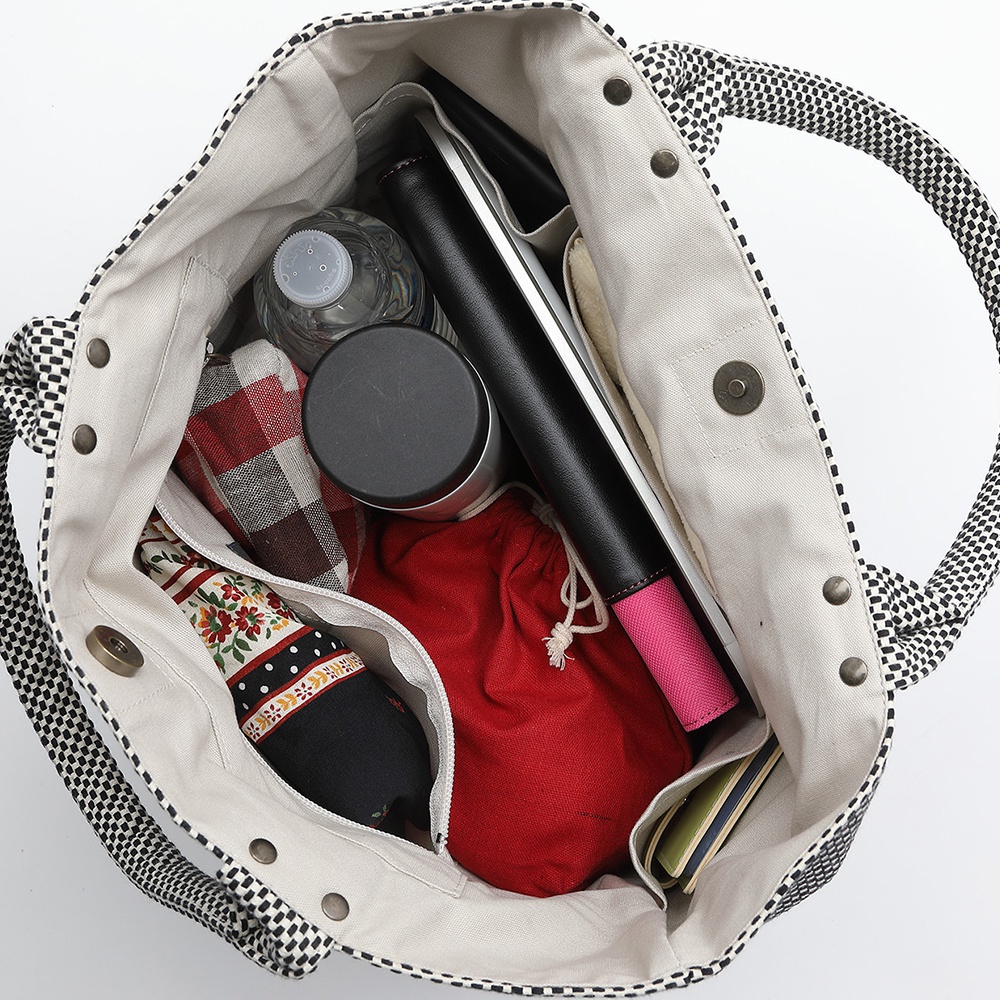 三河木綿刺子織大開口托特包，黑色格紋帆布外觀，內部裝有水瓶、保溫杯、平板電腦、紅色束口袋及其他小物，設計簡約實用。