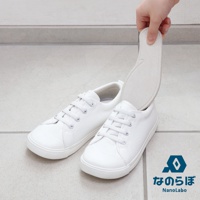 一隻手正將一塊米白色的鞋墊放入一隻同樣米白色的帆布鞋中，另一隻同款的帆布鞋放在一旁。